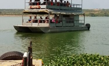 Safari boat named HIPPO with passengers cruising on a lake.